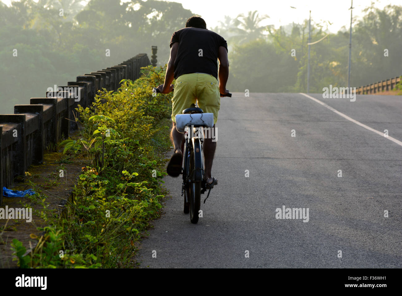 Ein Junge, Radfahren in der Nerull Brücke, Nerull, Goa. Stockfoto