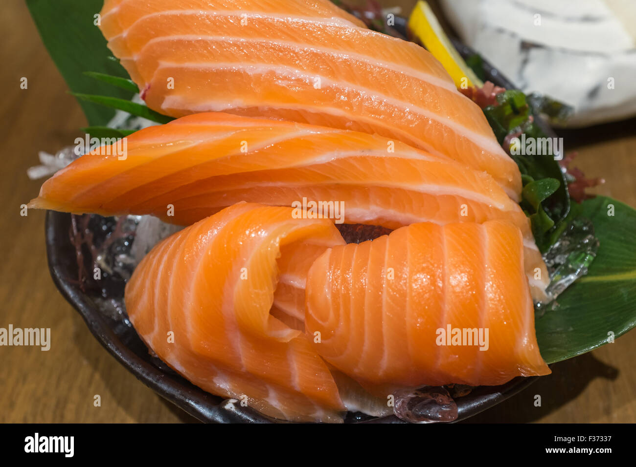 Lachs-Sashimi über Eis auf schwarz Schüssel Stockfoto