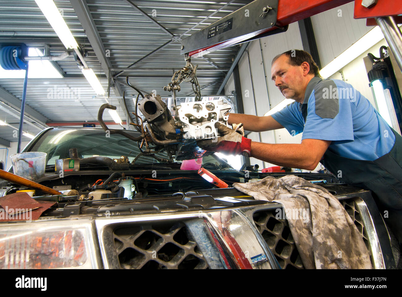 Kfz-Mechaniker ist bei der Arbeit mit dem Austausch des Zylinderkopfes eines PKW Stockfoto