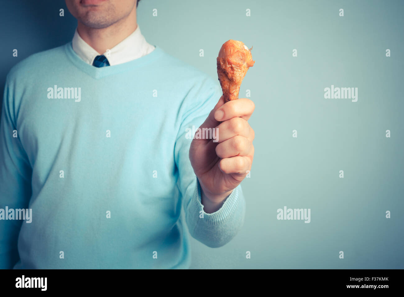 Ein junger Mann hält eine geröstete Hühnerbein Stockfoto