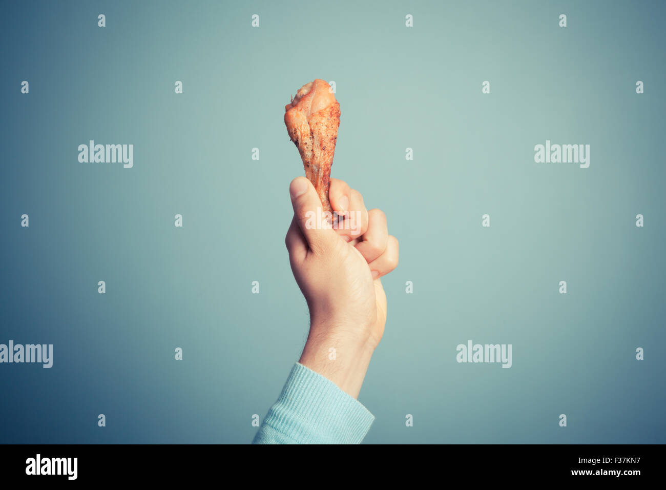 Ein junger Mann hält eine geröstete Hühnerbein Stockfoto