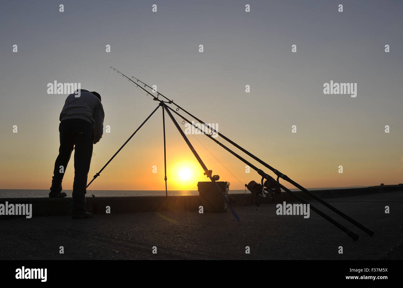 Angelruten und Fischer bei Sonnenuntergang am Ende der Porthcawl Hafen Wand. Süd-Wales. VEREINIGTES KÖNIGREICH. 30.09.2015. OBLIGATORISCHE Kredit Gar Stockfoto