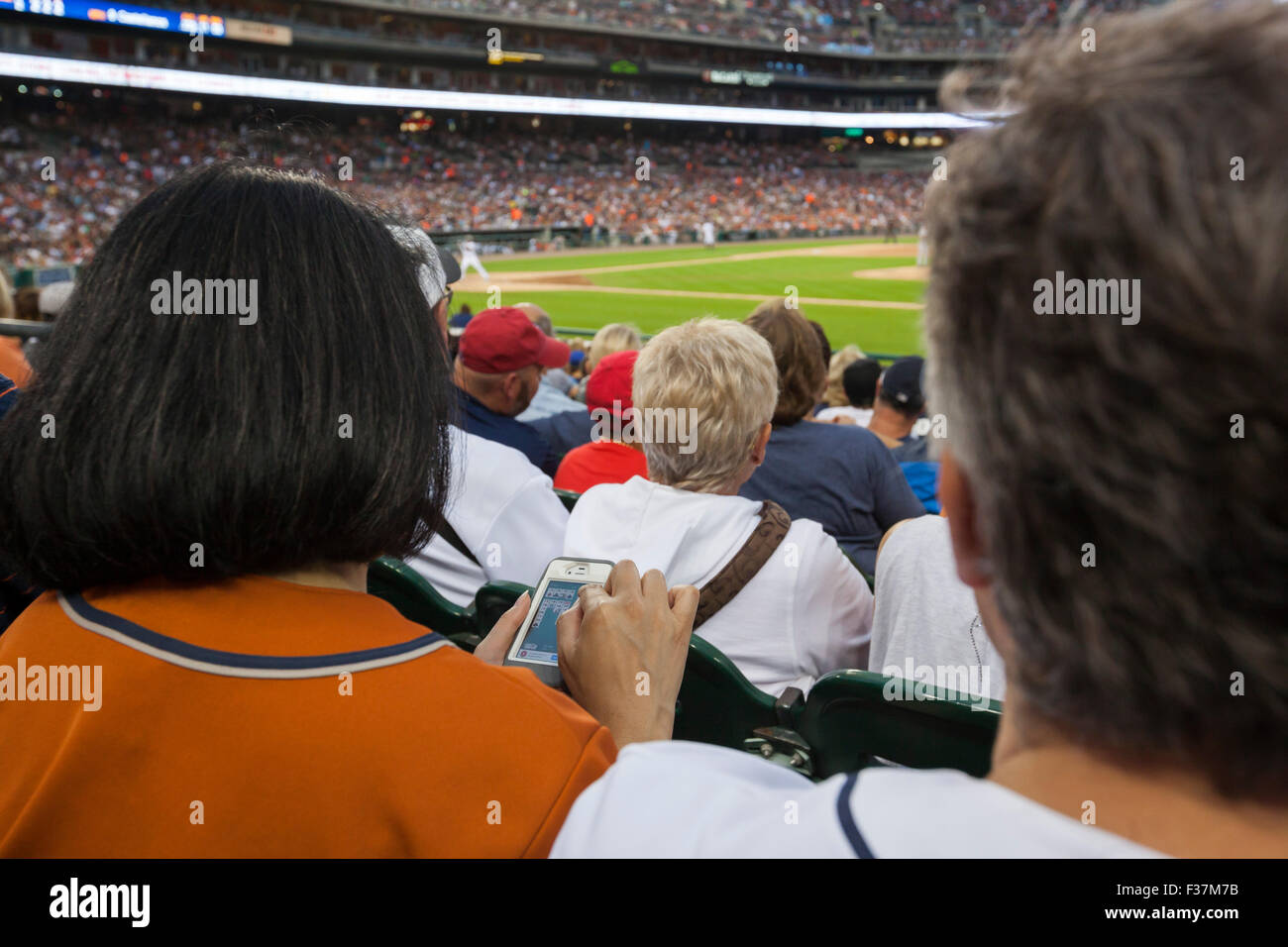 Detroit, Michigan - eine Frau spielt Solitär auf ihr Handy im Comerica Park bei einem Baseballspiel. Stockfoto