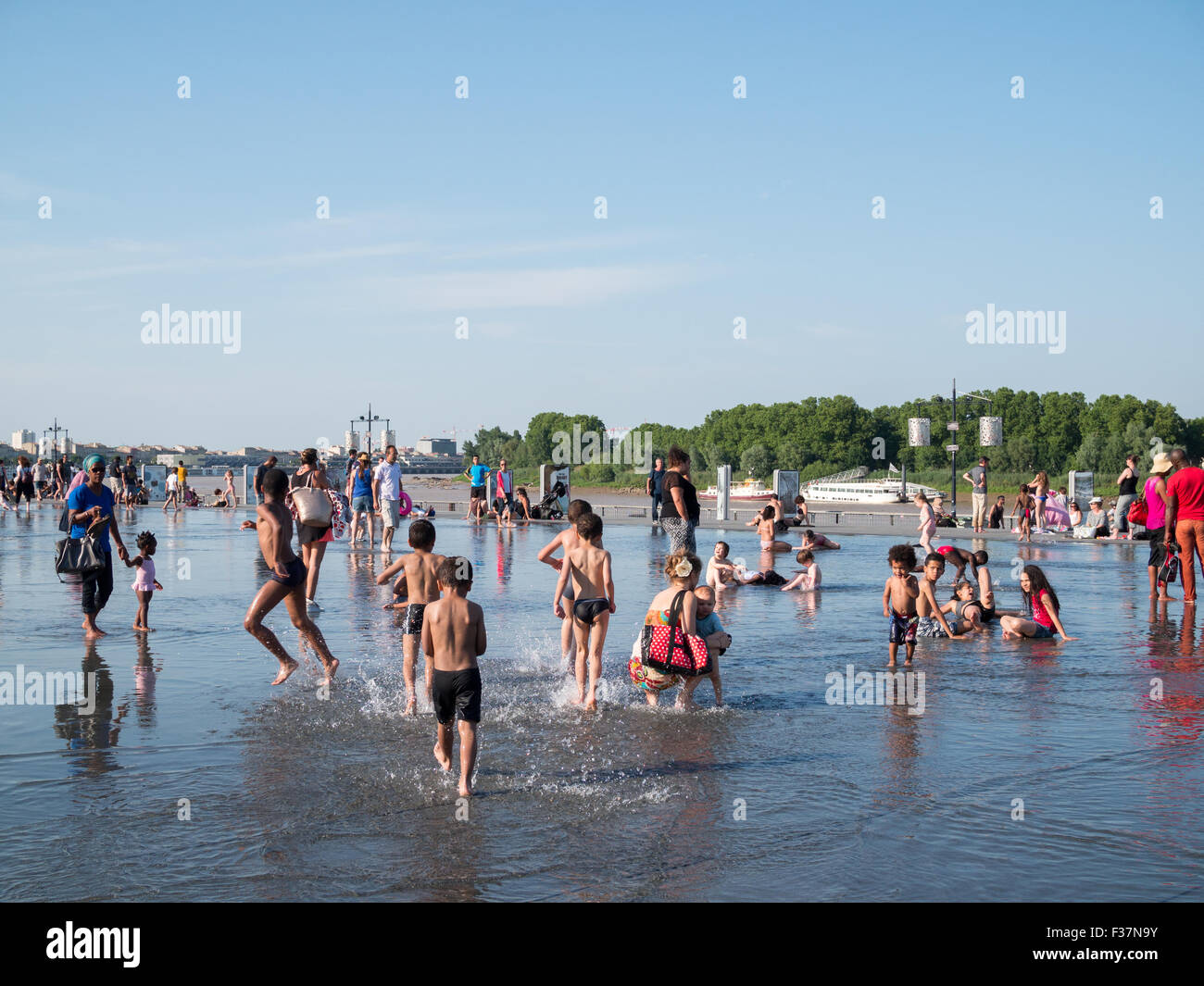 Kinder spielen im Wasser des Le Miroir d ' Eau Stockfoto