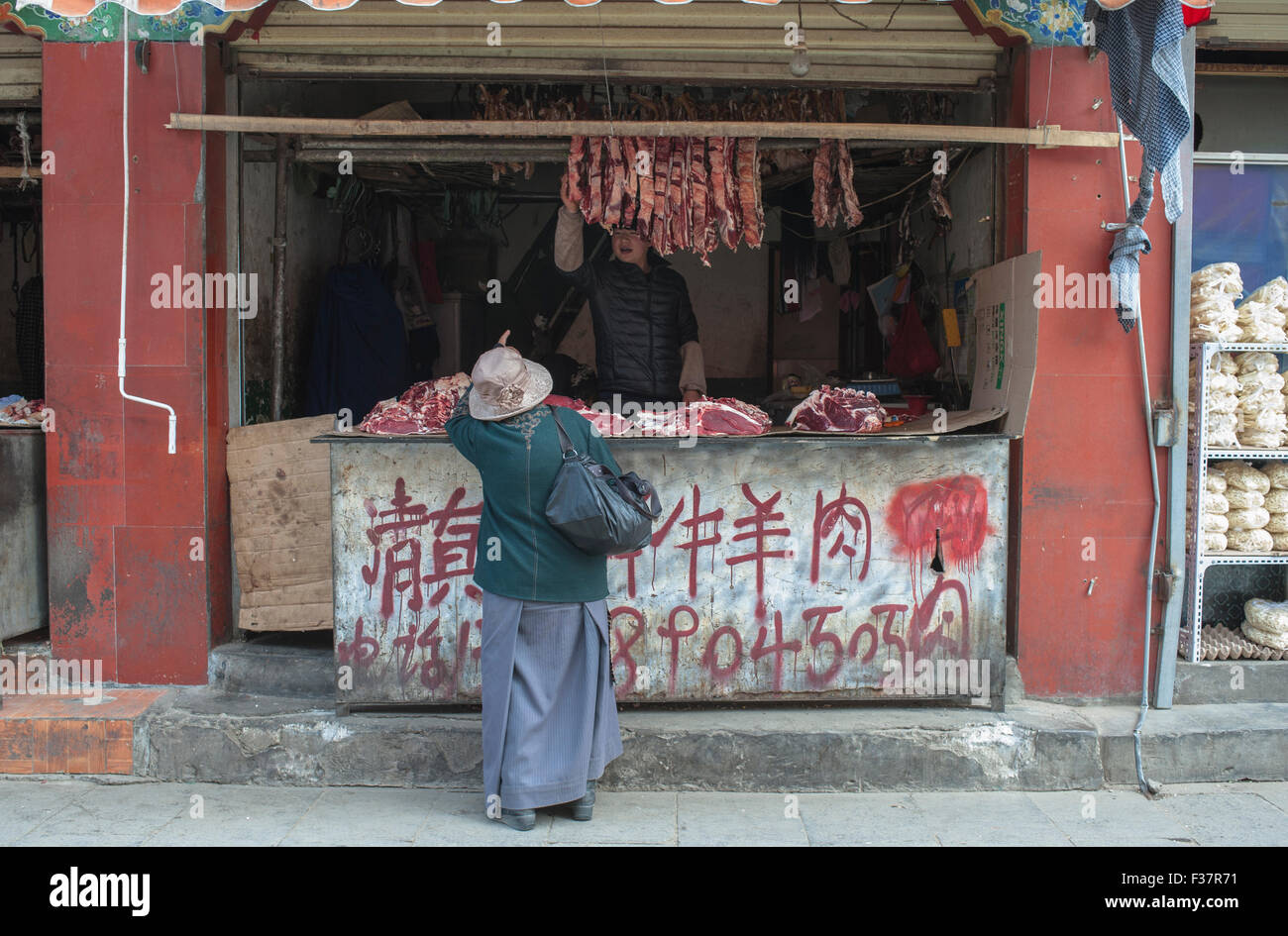 Metzger-Shop in Lhasa, Tibet. Eine Frau kauft Fleisch von einem Metzger in Tibet Stockfoto