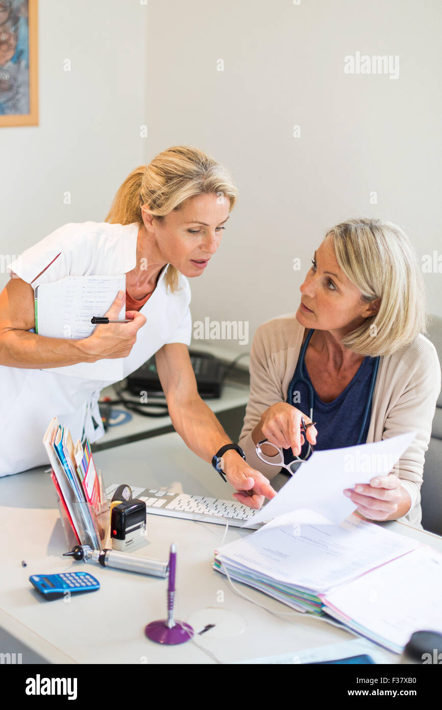 Arzthelferin erhält Anweisungen des Arztes, die sie unterstützt. Stockfoto