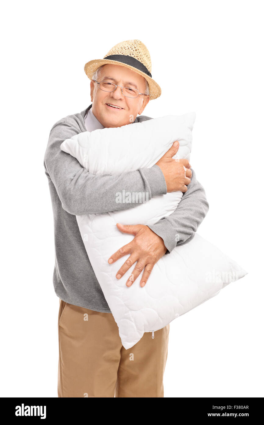 Vertikale Aufnahme eines fröhlichen senior Gentleman eine weiße Kissen umarmt und schaut in die Kamera, die isoliert auf weißem Hintergrund Stockfoto