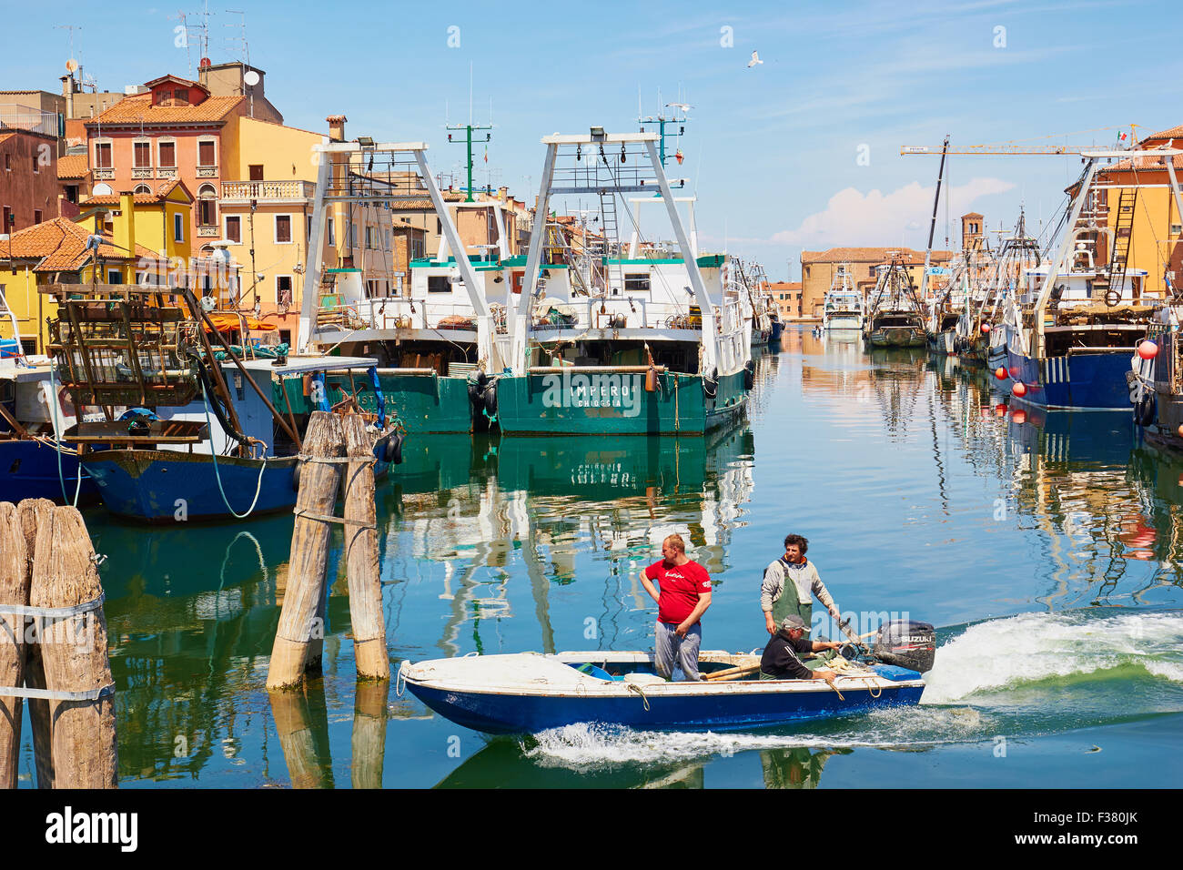 Kleines Fischerboot am Kanal mit Fischkuttern im Hintergrund Chioggia venezianischen Lagune Veneto Italien Europa Stockfoto