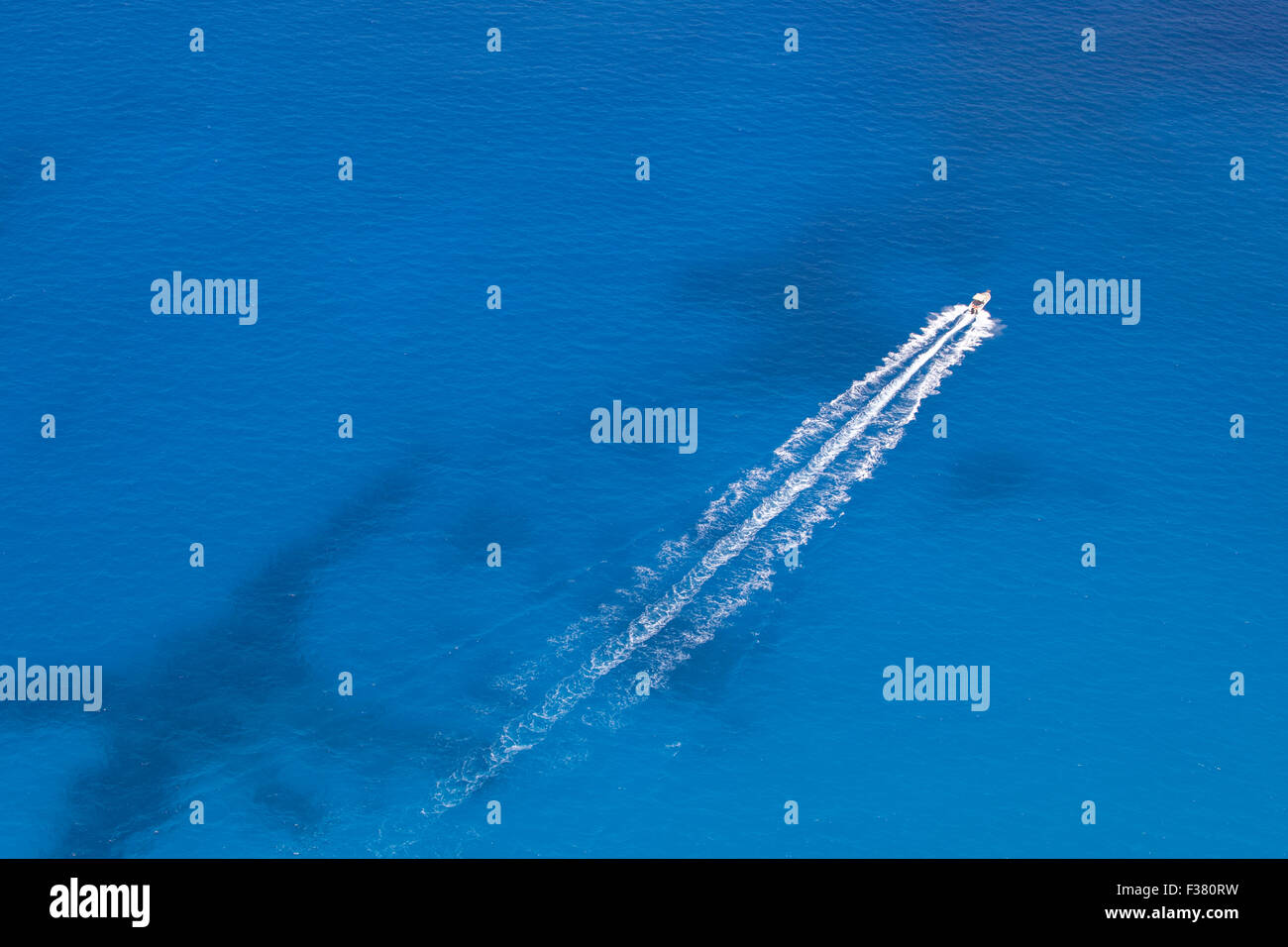 Luftaufnahme von Motorboot in einem türkisblauen Meerwasser schweben. Das Boot bewegt sich diagonal durch den Rahmen des Bildes. Stockfoto