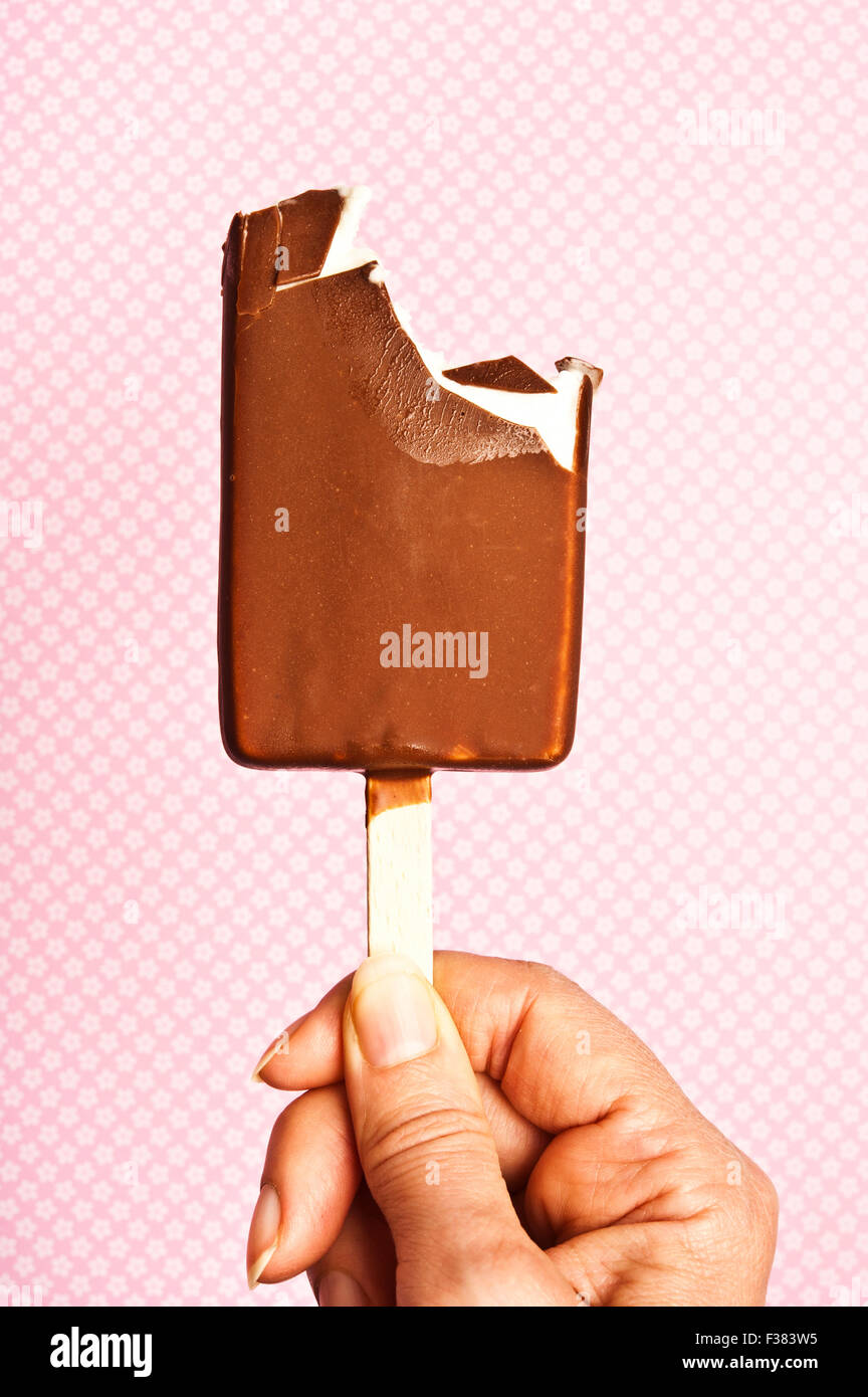 Frau Hand hält eine teilweise gegessen Schokolade Eis am Stiel Stockfoto