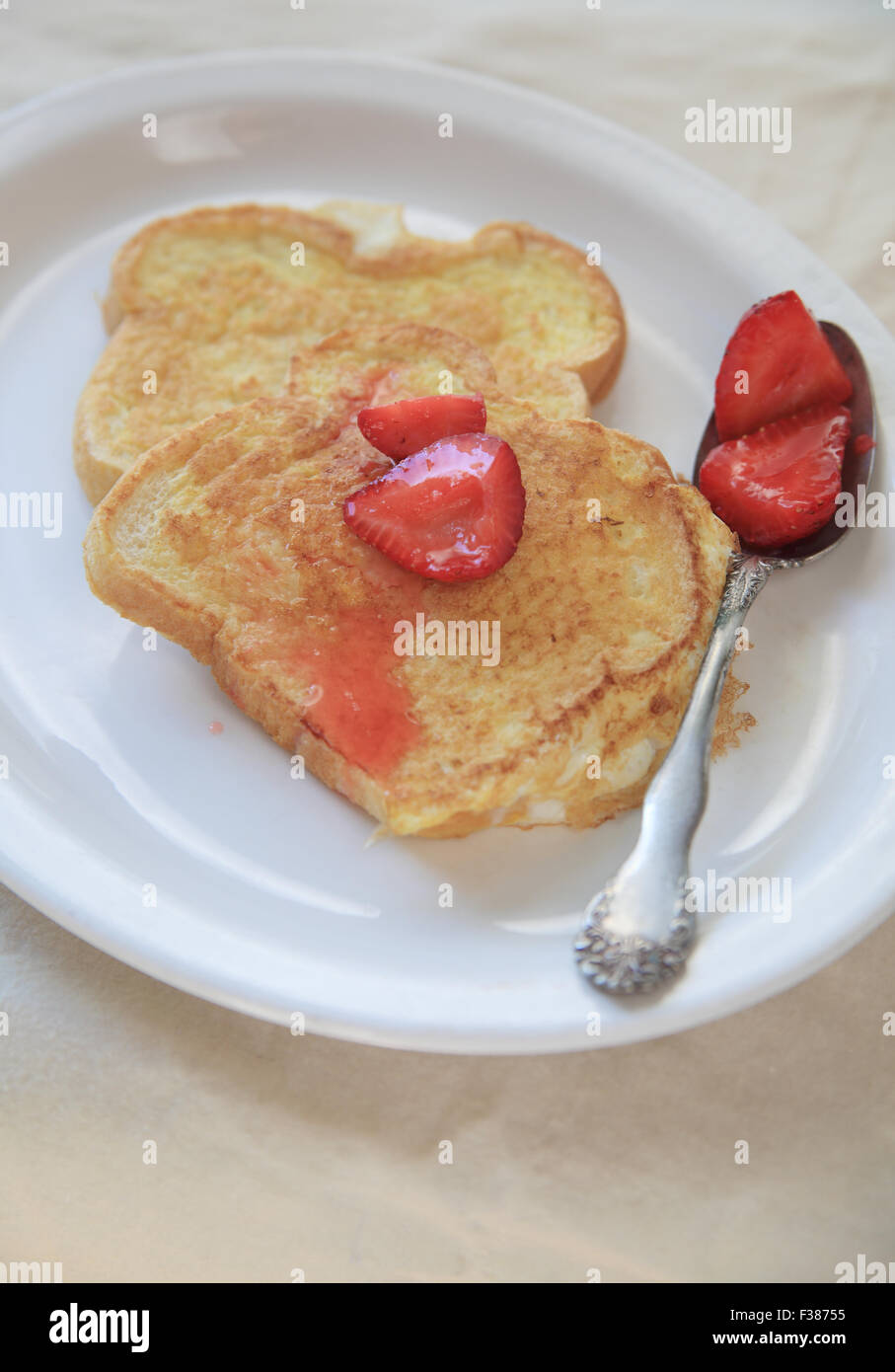 Eingelegten Erdbeeren über French Toast auf einem weißen Teller gelöffelt Stockfoto