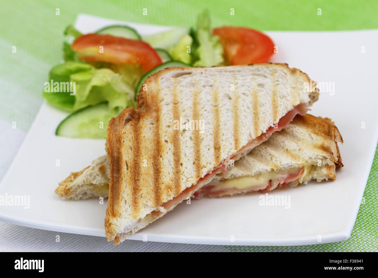 Toast mit Schinken und Käse und grünem Salat auf weißen Teller Stockfoto