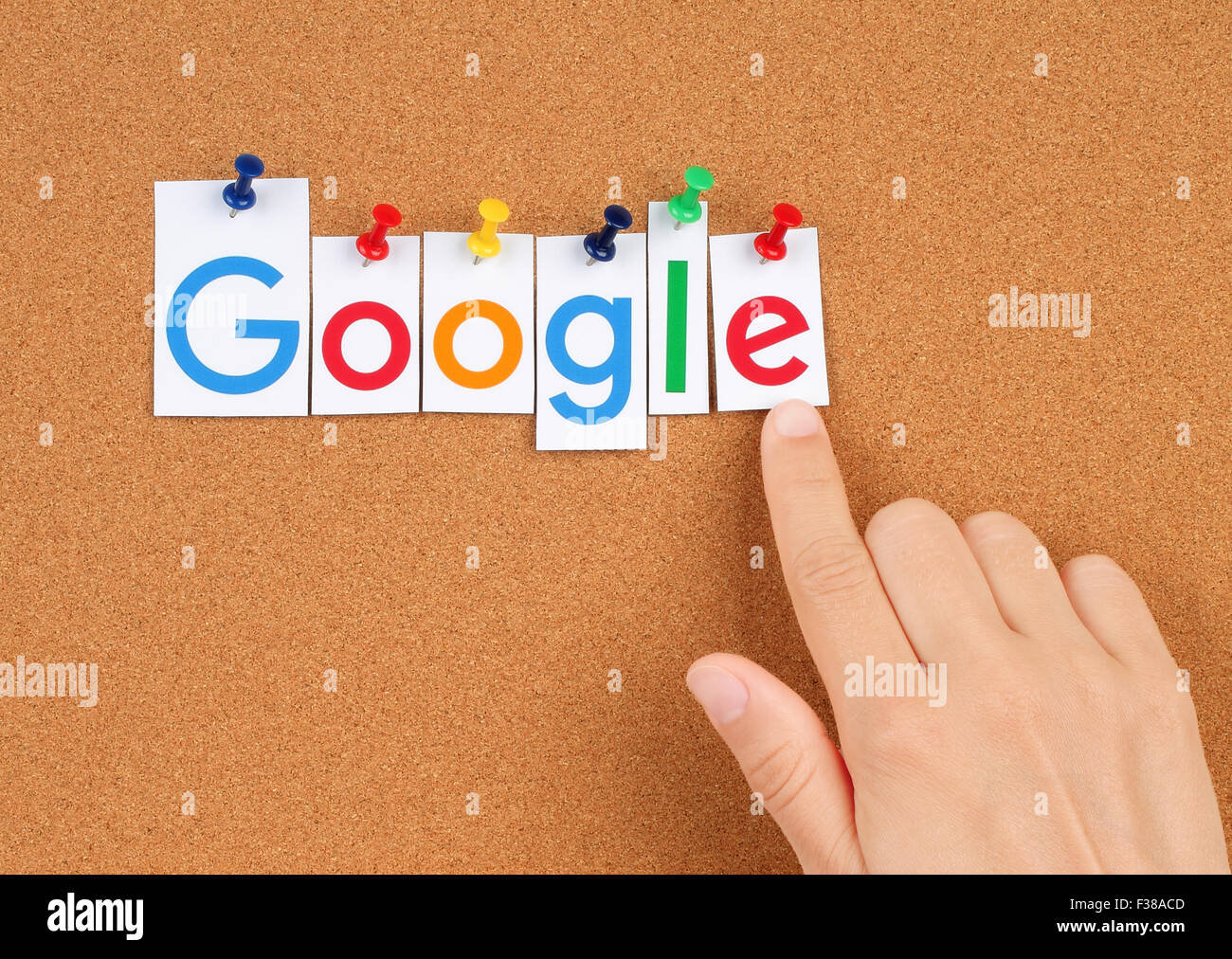 Neue Google-Logo auf Papier gedruckt, geschnitten und auf Kork-Pinnwand mit Hand festgesteckt. Google ist multinationales Unternehmen der USA. Stockfoto