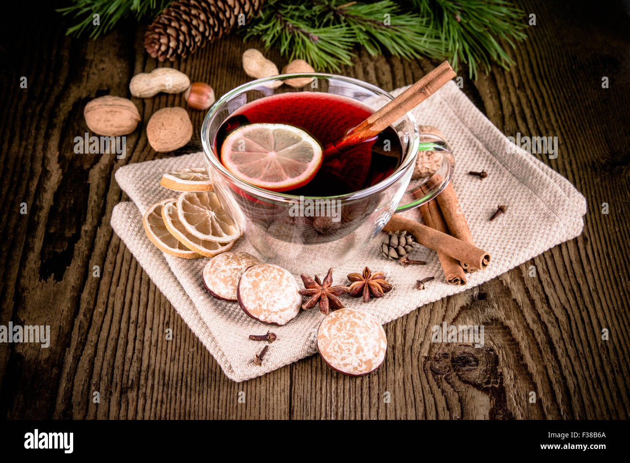 Glühwein in Glas mit Zimtstange, Lebkuchen und Nüssen, Nahaufnahme Stockfoto