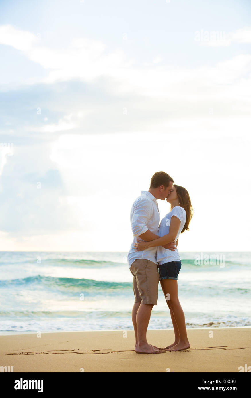 Romantische glückliches junges Paar küssen am Strand bei Sonnenuntergang Stockfoto