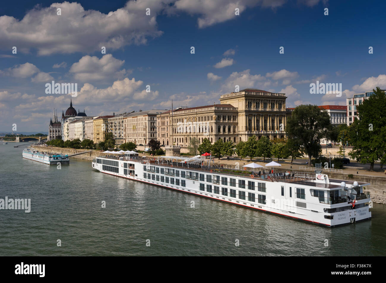 Ein Wikinger-Kreuzfahrt-Schiff vertäut am Ufer der Donau mit der ungarischen Akademie hinter in Budapest, Ungarn. Stockfoto