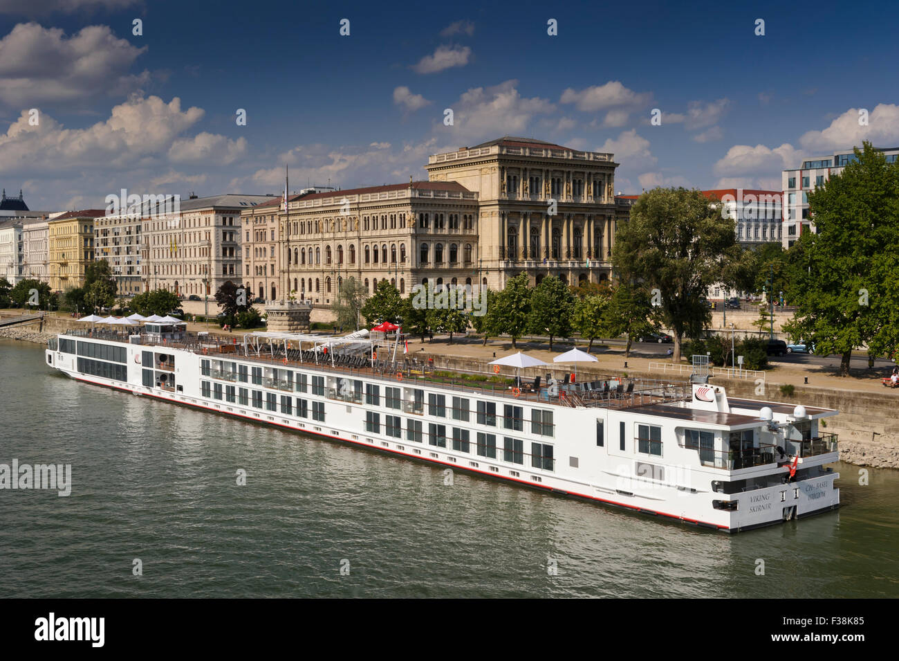 Ein Wikinger-Kreuzfahrt-Schiff vertäut am Ufer der Donau mit der ungarischen Akademie hinter in Budapest, Ungarn. Stockfoto