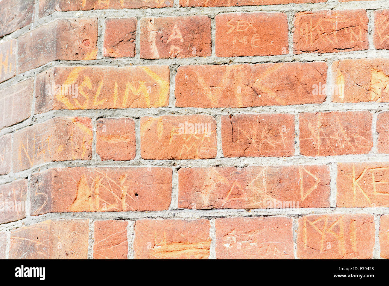 Graffiti in roten Backsteinmauer außerhalb Bedford County Court in Bedford, Bedfordshire, England gehauen Stockfoto