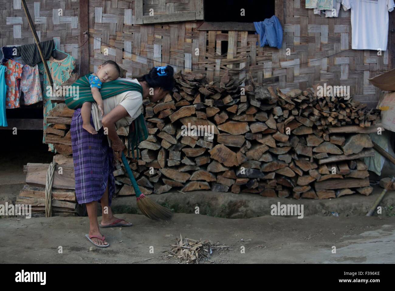 Myitgyina, Myanmar. 2. Oktober 2015. Eine Frau mit ihrem Kind auf dem Rücken fegt den Boden in einem Flüchtlingslager in Myitgyina, Myanmar, 2. Oktober 2015. Flüchtlinge in Myanmar nördlichsten Kachin Staat wächst von Jahr zu Jahr keine Reduktion aufgrund mehrjähriger Zusammenstöße bewaffnet, sagte ein Administrator eine kirchliche Flüchtlingslager in Myitgyina am 1. Oktober. Bildnachweis: U Aung/Xinhua/Alamy Live-Nachrichten Stockfoto