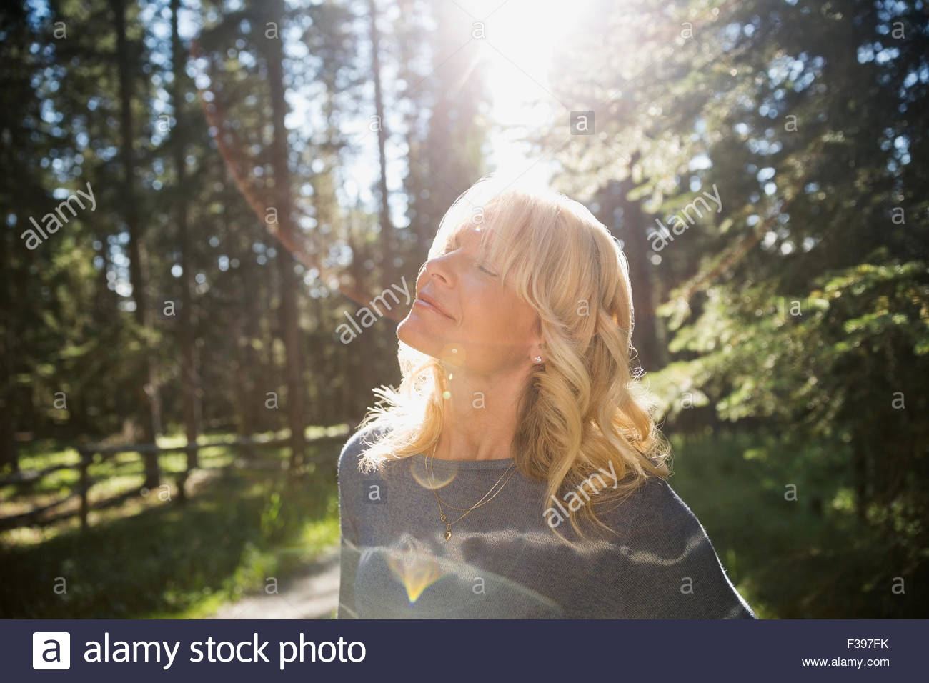 Heitere blonde Frau geschlossenen Augen in sonnigen Wald Stockfoto