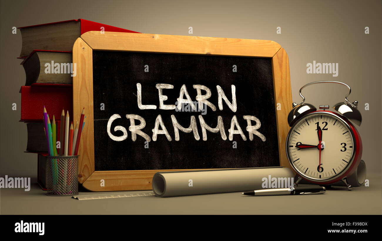 Handschriftliche motivierenden Zitat - Grammatik - auf einer Tafel. Komposition mit Tafel und Stapel Bücher, Wecker ein Stockfoto
