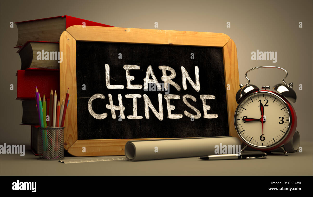 Lernen Sie Chinesisch - Tafel mit handgezeichneten Text, Stapel von Büchern, Wecker und Papierrollen auf der Hintergrund jedoch unscharf. Motivatio Stockfoto