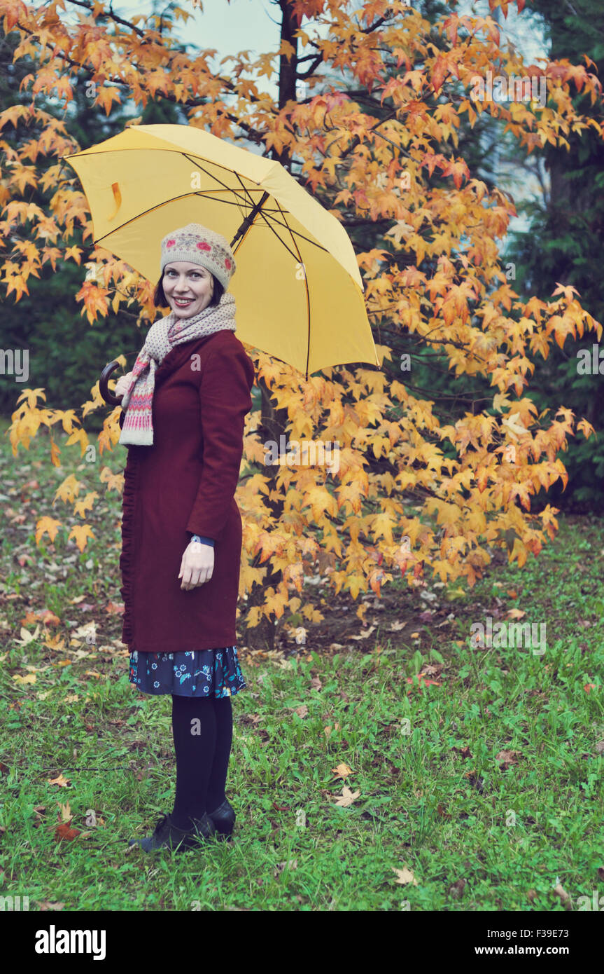 Frau im Park mit gelben Regenschirm Herbst Stockfoto