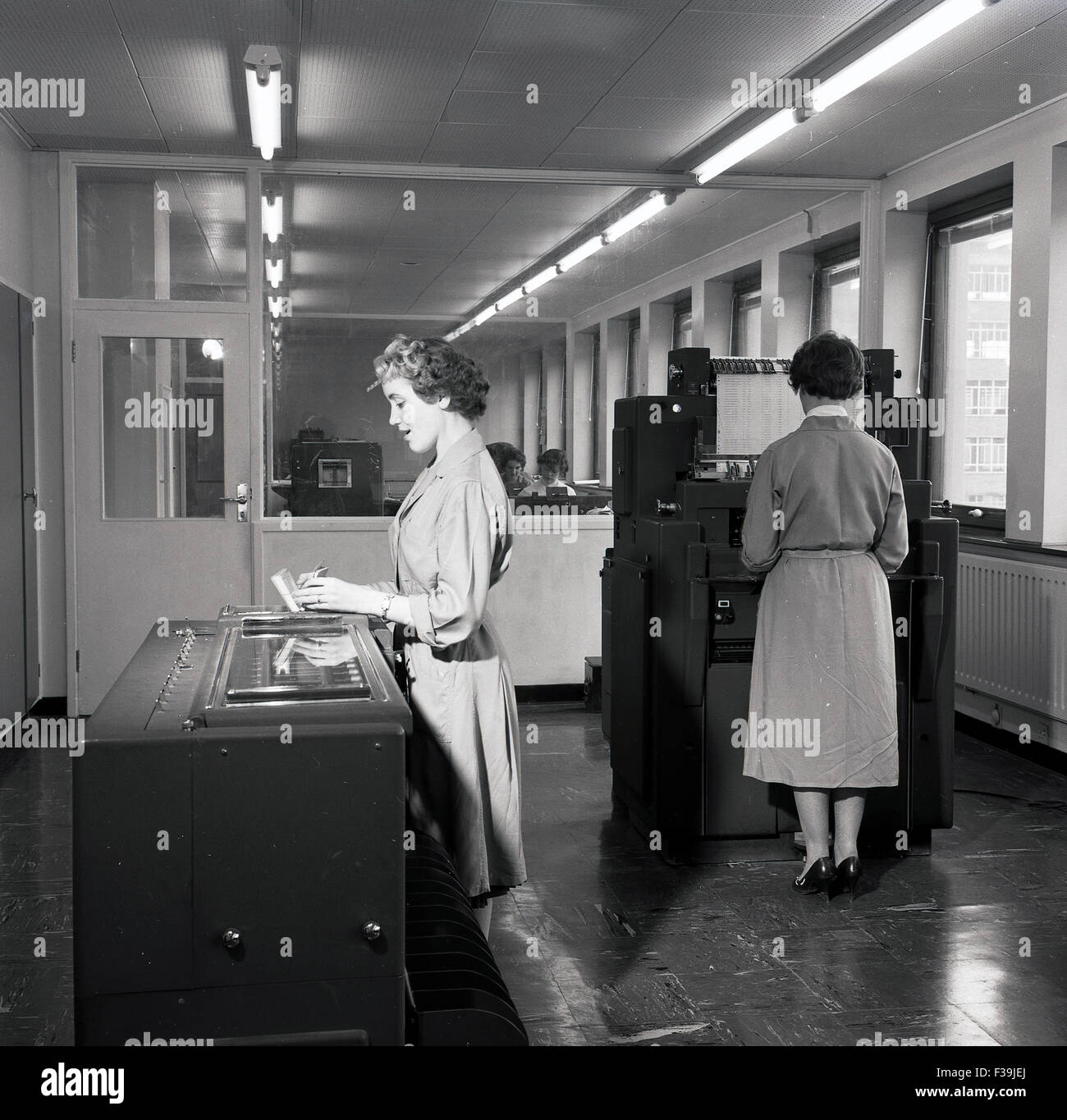 Historisches, 1950er Jahre, zwei weibliche Verwaltungspersonal mit großen Datenverarbeitung oder frühen Computer-Druckmaschinen. Stockfoto