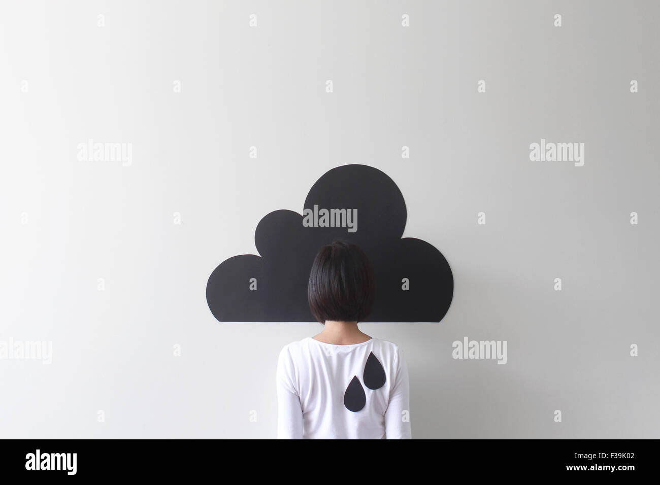 Rückansicht einer Frau, getarnt von einer konzeptuellen Regenwolke Stockfoto