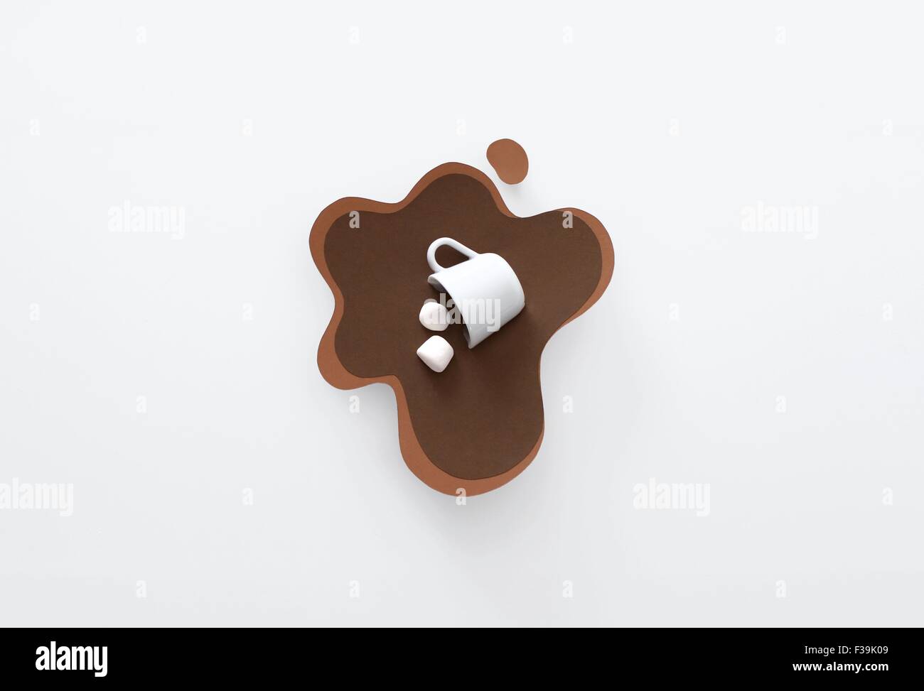 Konzeptueller Becher, der in einer Pfütze aus heißer Schokolade und Marshmallows liegt Stockfoto