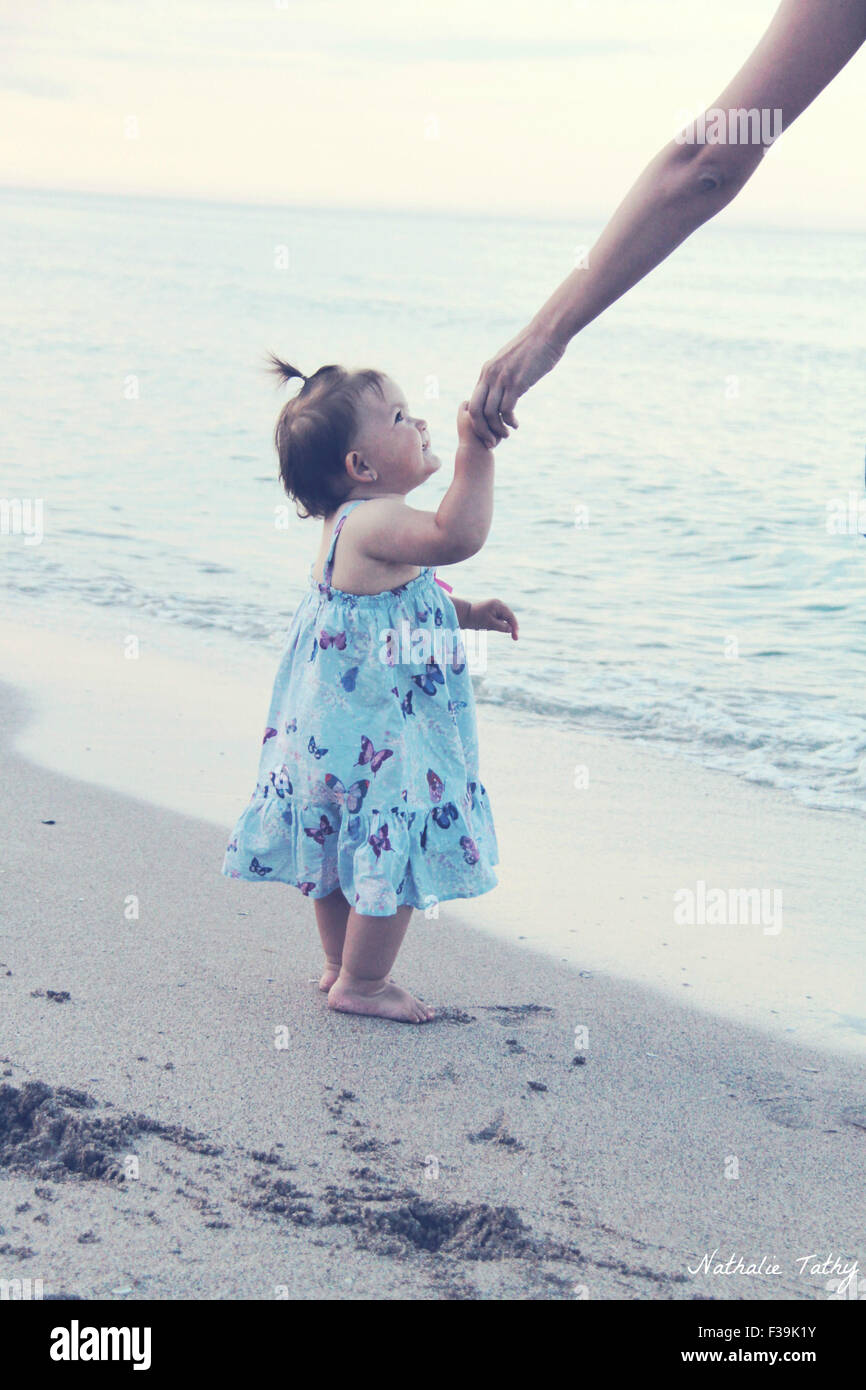 Babymädchen hielt ihre Mutter seiner Hand am Strand Stockfoto