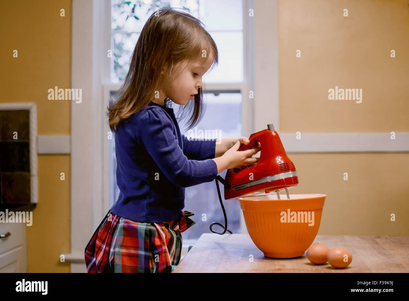 Mädchen mit einem elektrischen Mixer in der Küche Stockfoto