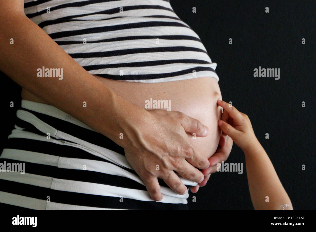 Schwangere Frau mit ihren Bauch und ihr kleines Mädchen berühren ihren Nabel Stockfoto