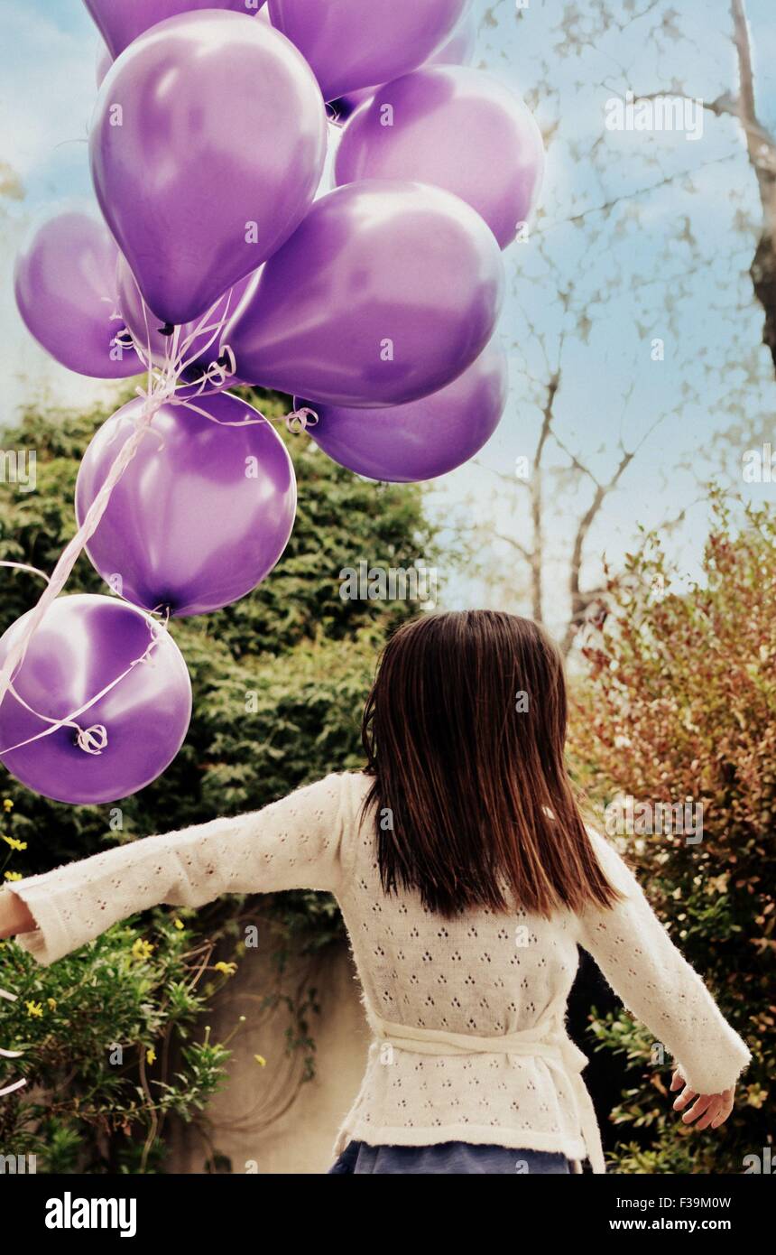 Rückansicht eines Mädchens mit einem Haufen lila Luftballons Stockfoto