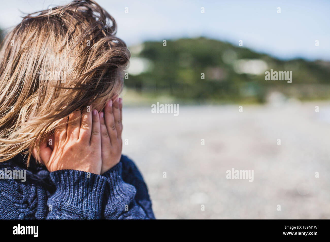 Kleinkind stehen am Strand bedeckte ihr Gesicht mit den Händen Stockfoto