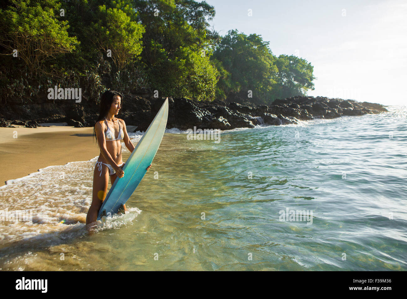 Frau, die in der Brandung steht und ihr Surfbrett hält, Bali, Indonesien Stockfoto