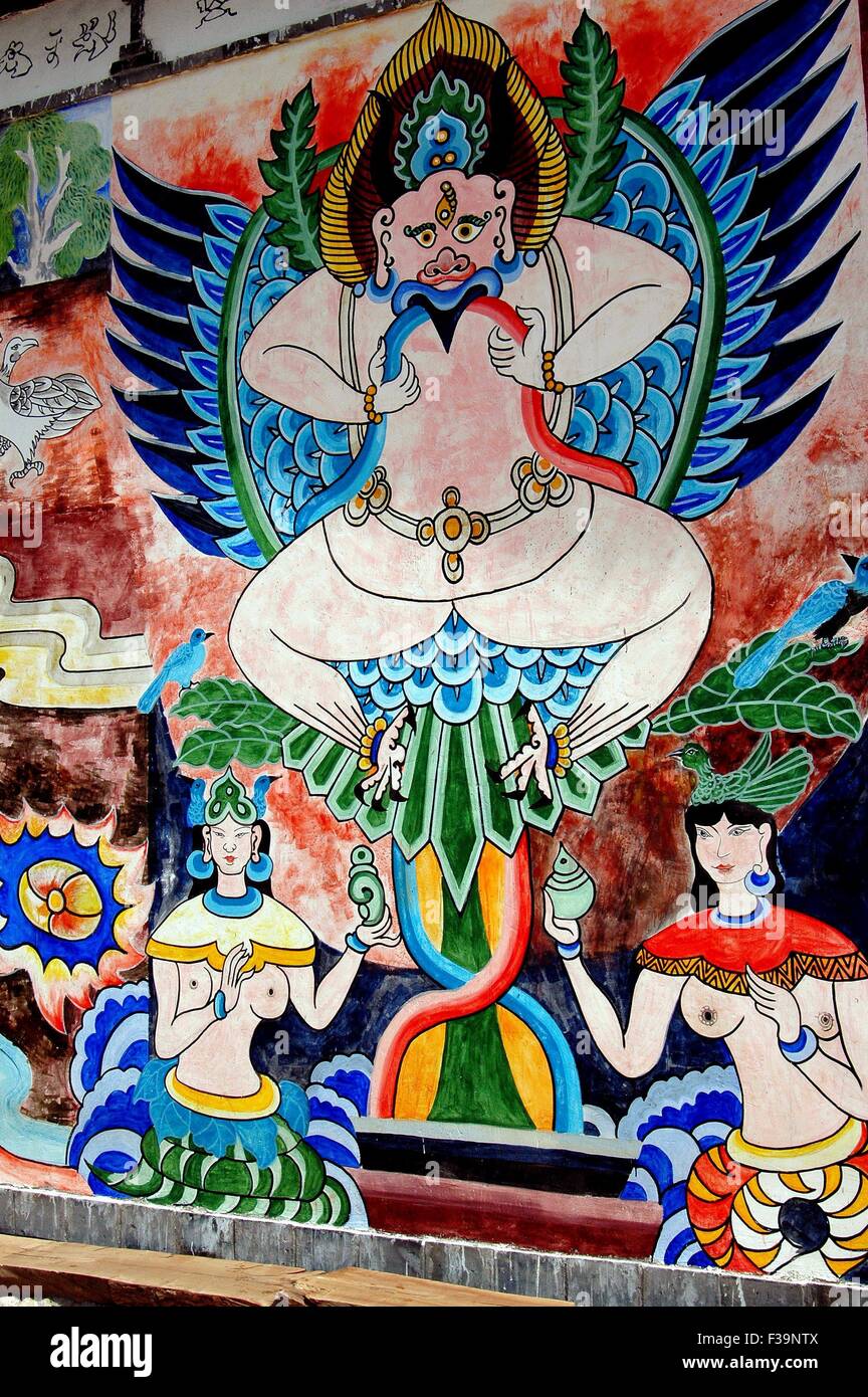 Guan Yin Xia, China: Fresken in einem Pseudo-Hindu-Stil auf einem Naxi-Haus zeigen eine geflügelte Gottheit, flankiert von zwei Frauen Stockfoto