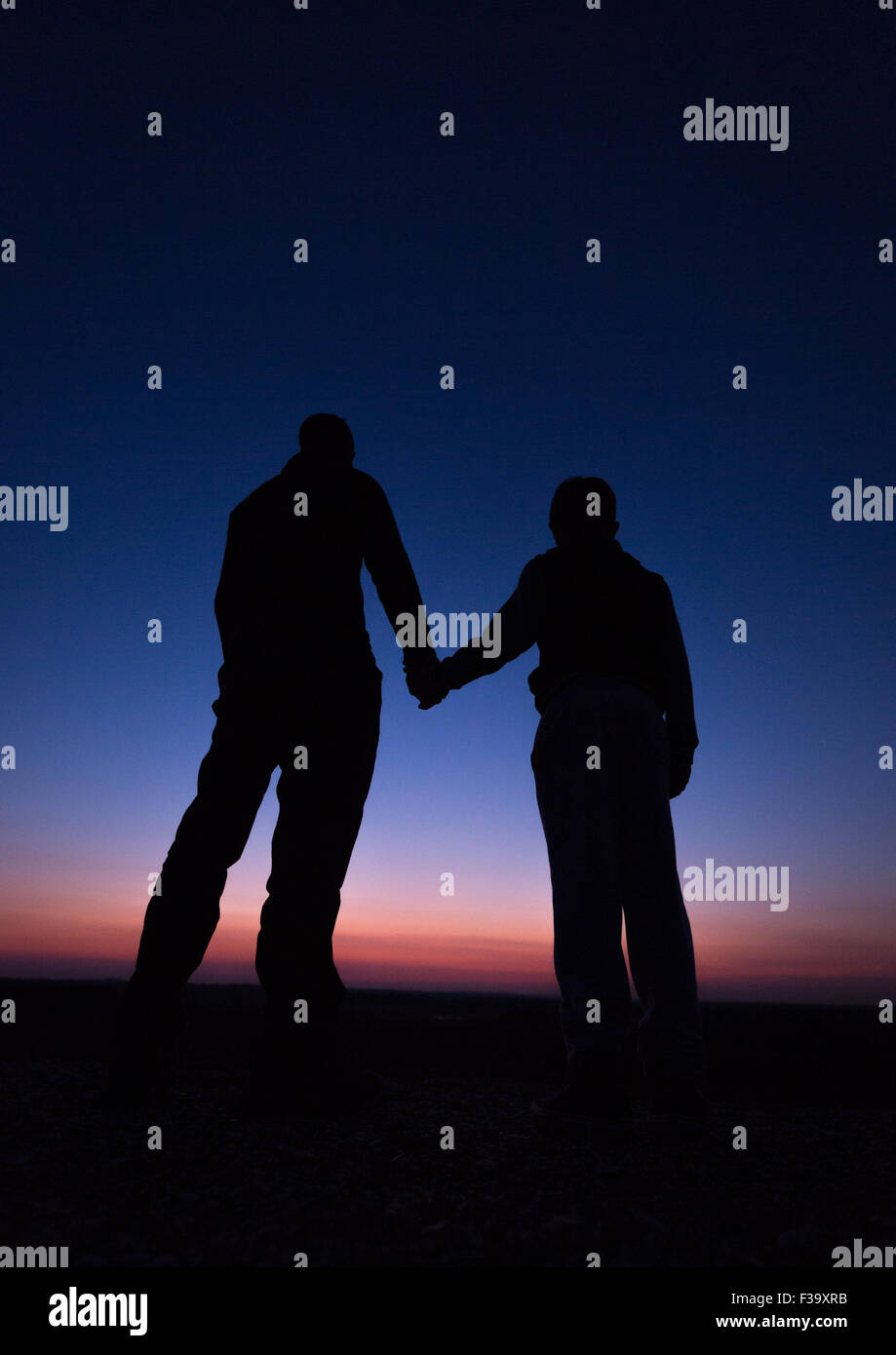 Förderung und Erziehung Konzept Foto von Vater und Sohn in der Silhouette, die Hand in Hand, den Sonnenuntergang beobachten Stockfoto