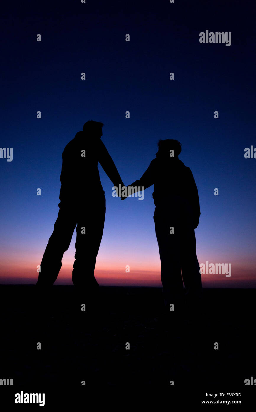 Förderung und Erziehung Konzept Foto von Vater und Sohn in der Silhouette, die Hand in Hand, den Sonnenuntergang beobachten Stockfoto