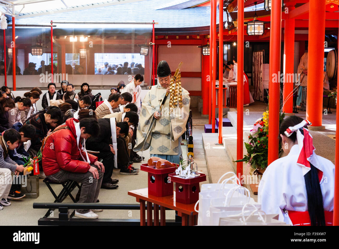Japanischen Shinto Priester, kannushi, tragen, Hut und eboshi kariginu Kleidungsstück ein Segen auf sitzen Leute an ikuta Heiligtum in Kobe im Neuen Jahr. Stockfoto