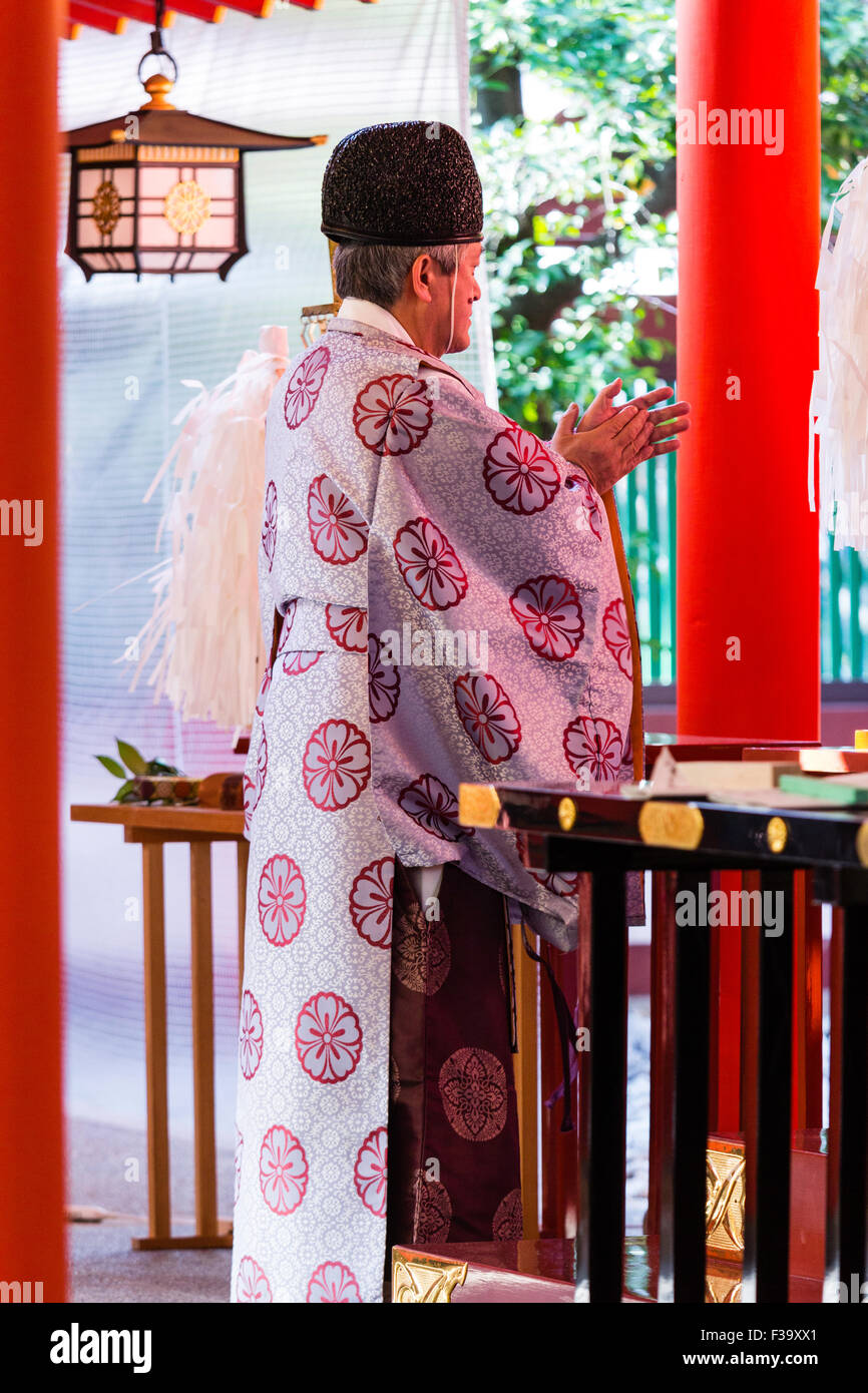 Japan, Shinto Schrein. Ältere Priester, Kannushi, AKA Shinshoku, tragen Kariginu eboshi Hut und Kleid, Claps, während vor Angst Bereich der Schrein der Halle. Stockfoto