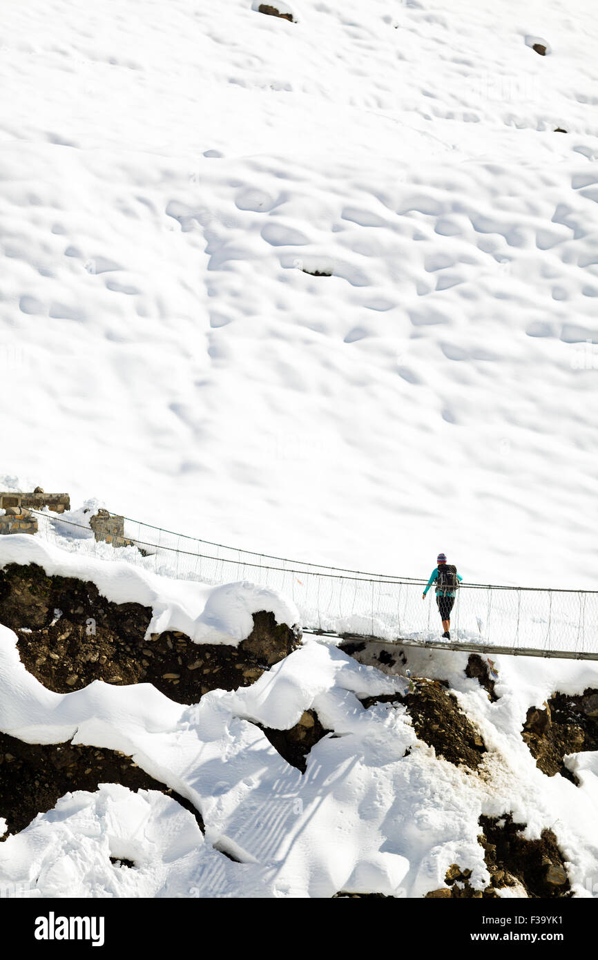 Junge Frau Wanderer zu Fuß auf die Brücke in schöne inspirierende Winterbergen im Himalaya. Wandern, Inspiration und Motivation, Stockfoto