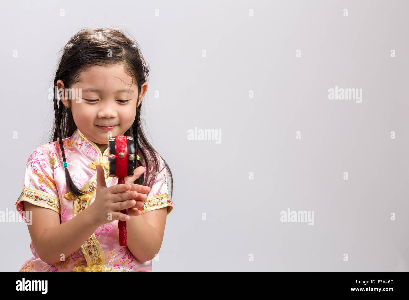 Kleine Mädchen spielen chinesische Spielzeug Trommel auf weißem Hintergrund. Stockfoto