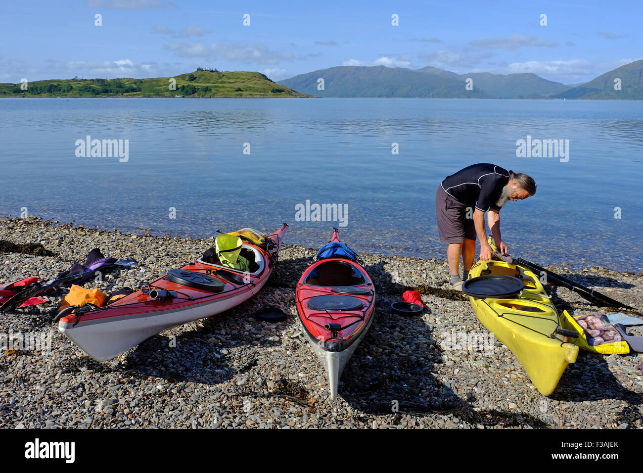 Mann Vorbereitung Kajaks auf Loch Linnhe an der Westküste von Schottland, Shuna Insel in naher Entfernung zum Start in den Ruhestand Stockfoto