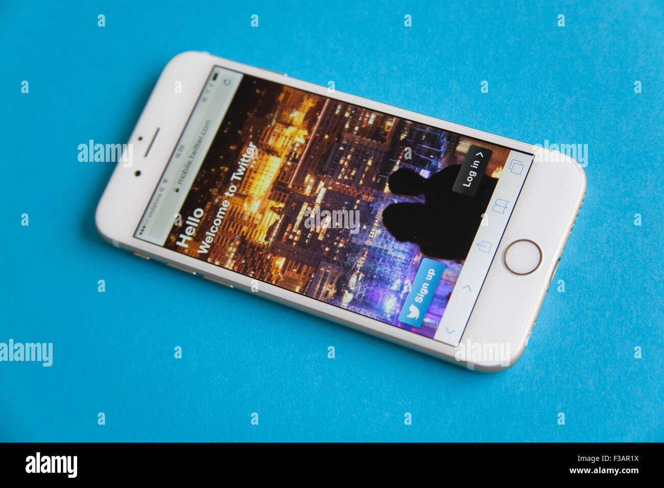 Gold und weiße Apple iPhone 6 mit Twitter anmelden Bildschirm vor einem blauen Hintergrund Stockfoto