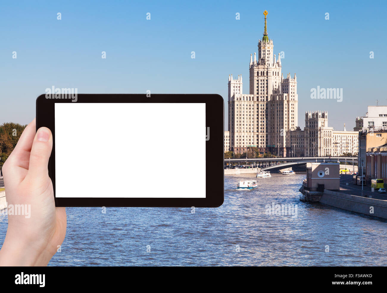 Reisen Sie Konzept - Hand hält TabletPC mit Bildschirm und Moskau Vysotka ausgeschnitten - Hochhaus im Hintergrund Stockfoto