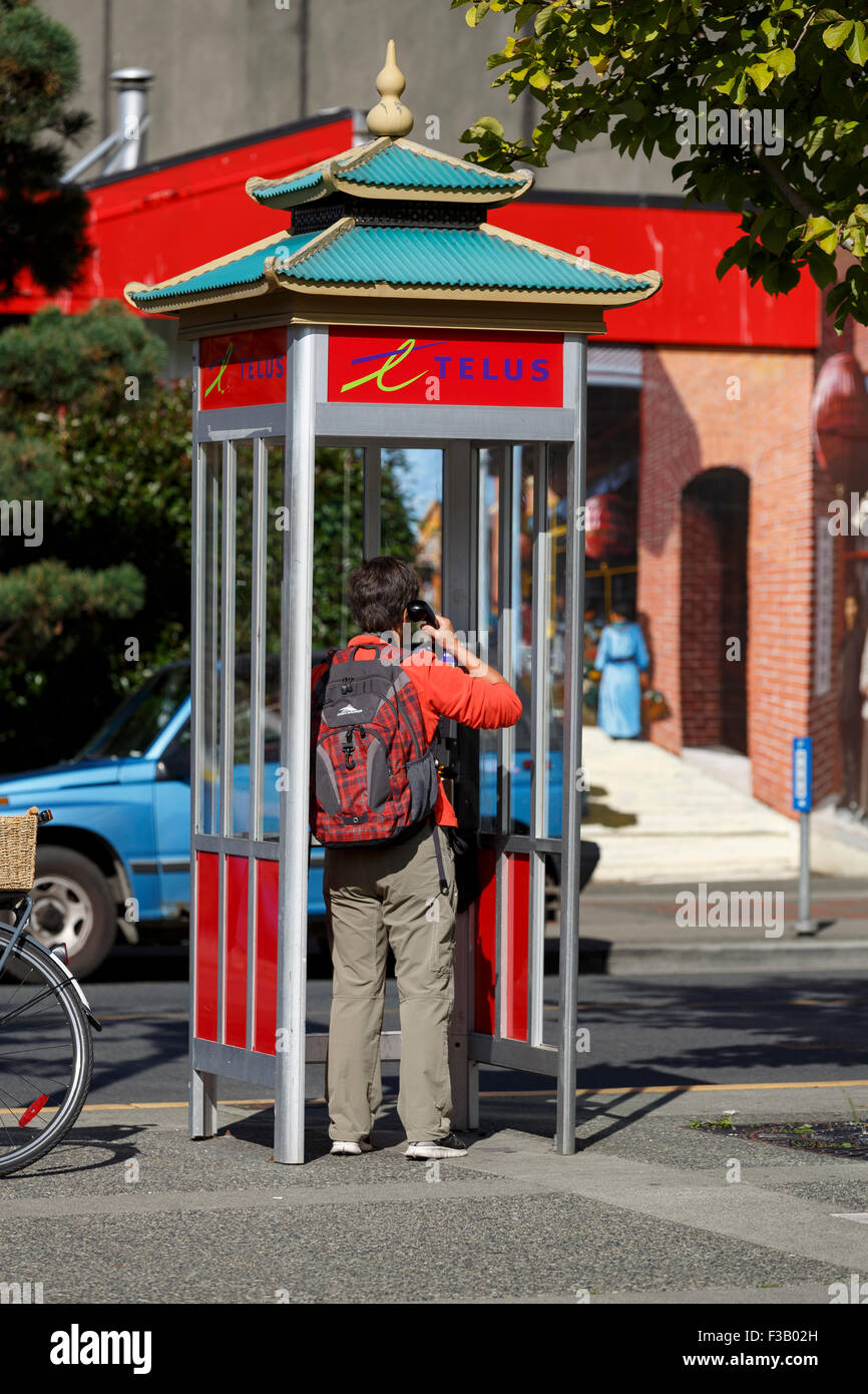 Person, die einen Anruf von einer Telefonzelle in Chinatown Victoria British Columbia Stockfoto