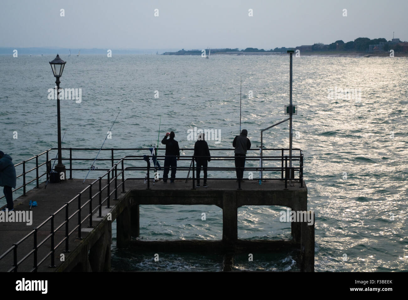 3 Personen-Fisch von einem Pier im Hafen von Portsmouth, Hampshire, England. Stockfoto