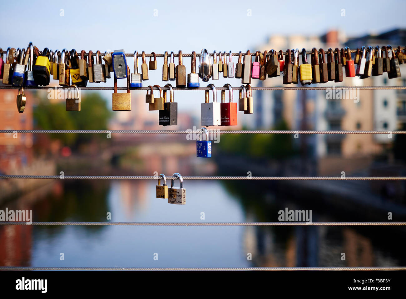 Vorhängeschlösser, die an Drahtgeländern der Centenary Bridge über den Fluss Aire im Calls-Gebiet von Leeds, Yorkshire, befestigt sind. VEREINIGTES KÖNIGREICH Stockfoto