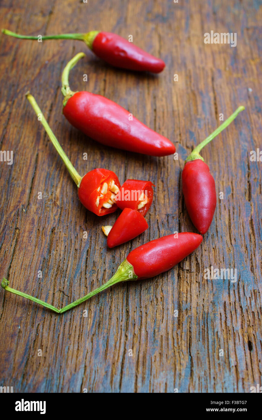 Rot-heiß in Scheiben geschnitten und ganze Paprika auf einem rustikalen hölzernen Hintergrund Stockfoto